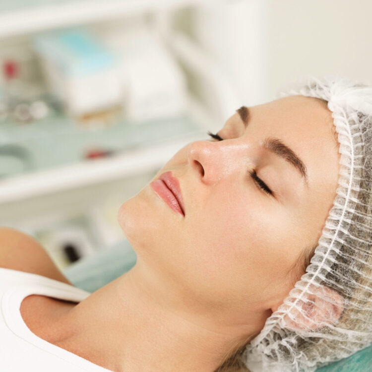 Beautiful young woman wearing sterile hat before treatment in aesthetic medical clinic
