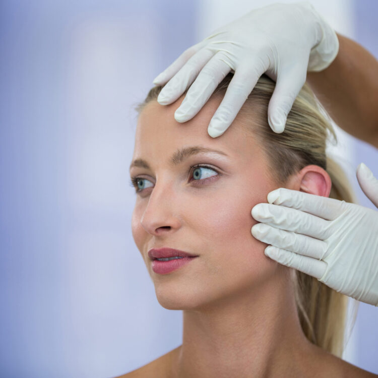 Doctor examining female patients face from cosmetic treatment